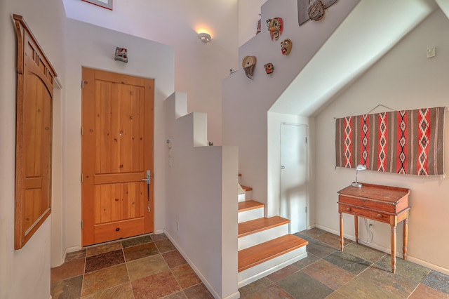 entrance foyer featuring stairway, stone tile flooring, and baseboards