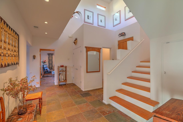 hall featuring recessed lighting, a high ceiling, visible vents, baseboards, and stairway