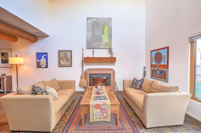 living room featuring a healthy amount of sunlight, a lit fireplace, visible vents, and baseboards