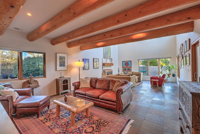 living area featuring beamed ceiling, stone tile flooring, visible vents, and recessed lighting