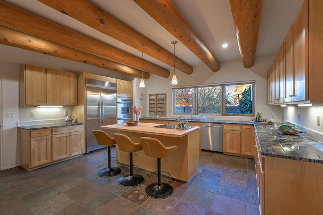 kitchen with light brown cabinets, a kitchen island, a kitchen breakfast bar, appliances with stainless steel finishes, and stone finish floor