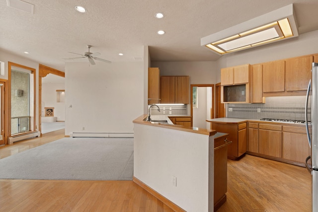 kitchen featuring a peninsula, baseboard heating, light countertops, a baseboard heating unit, and a sink