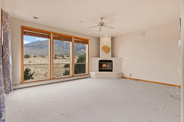 unfurnished living room with plenty of natural light, a glass covered fireplace, visible vents, and a mountain view