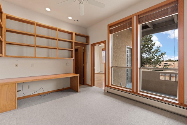 unfurnished office featuring light carpet, ceiling fan, baseboard heating, built in desk, and recessed lighting