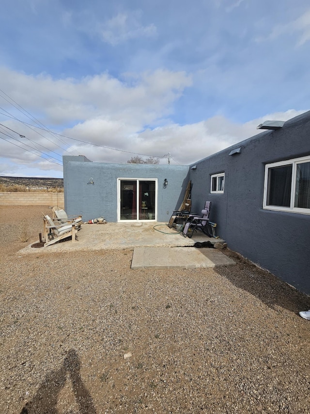 rear view of house featuring a patio and stucco siding