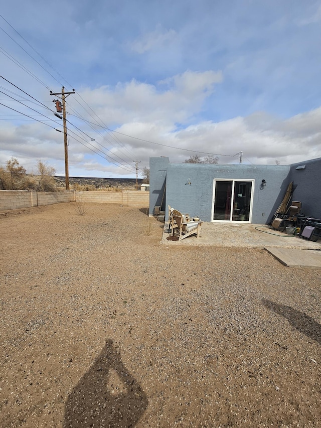 rear view of property featuring a patio area, fence, and stucco siding