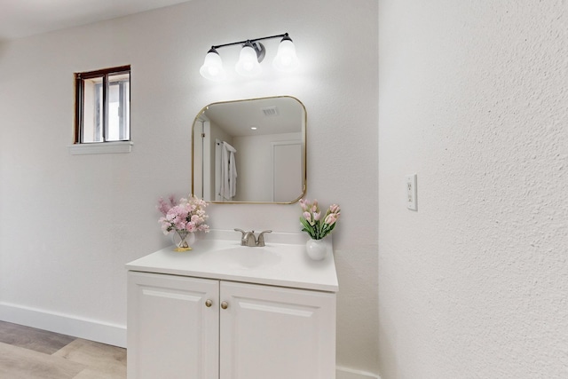 bathroom with visible vents, wood finished floors, vanity, and baseboards