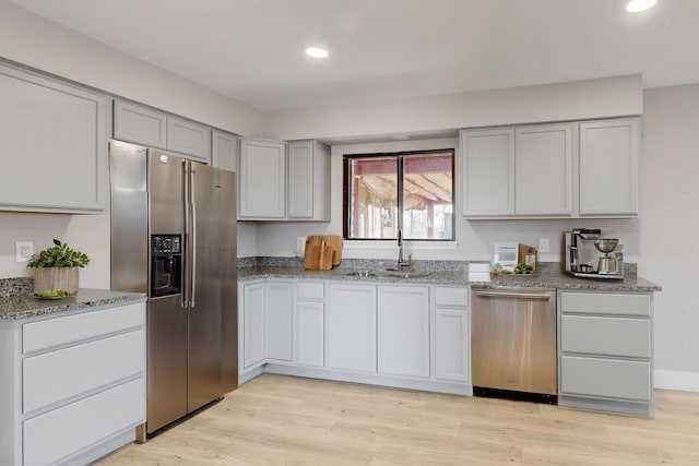 kitchen featuring appliances with stainless steel finishes, light wood-style floors, gray cabinets, and a sink