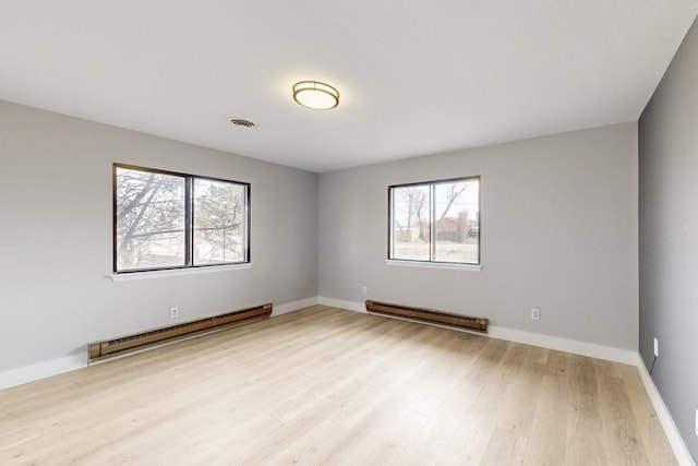 spare room with a baseboard heating unit, light wood-style flooring, and baseboards