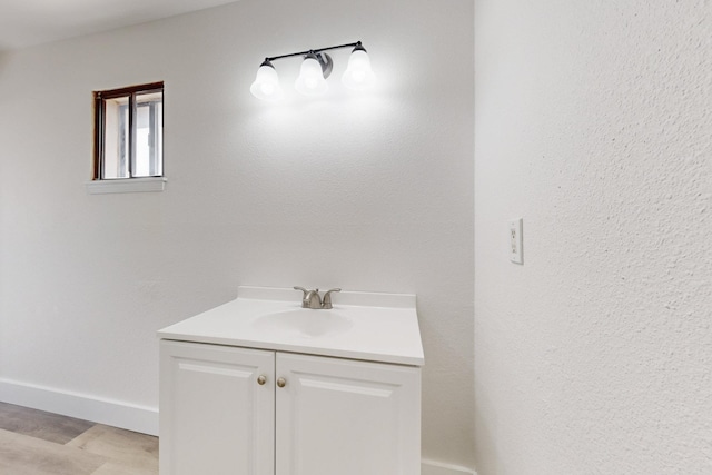 bathroom featuring a textured wall, baseboards, and vanity