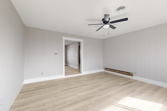 empty room with visible vents, baseboards, ceiling fan, light wood-type flooring, and a baseboard heating unit