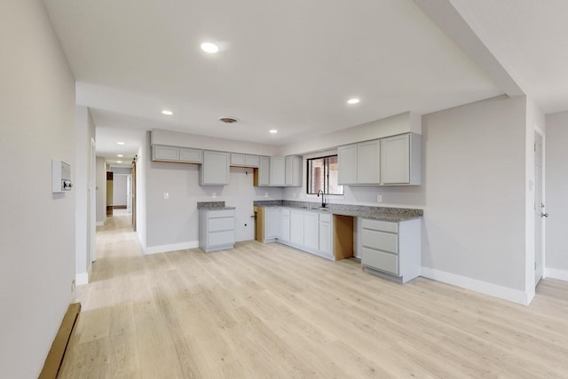 kitchen featuring light wood-type flooring, gray cabinets, and baseboards