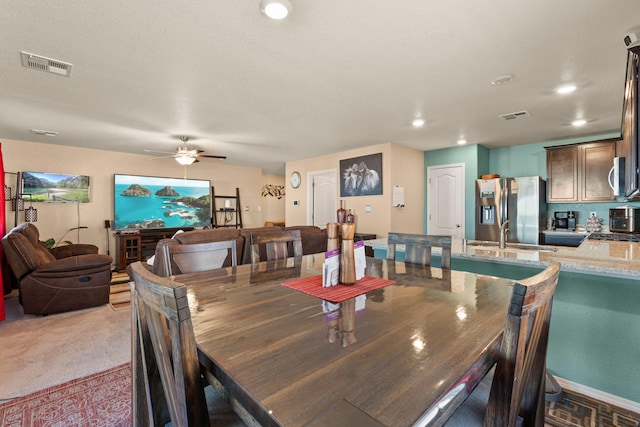 carpeted dining room featuring ceiling fan, visible vents, a sink, and recessed lighting