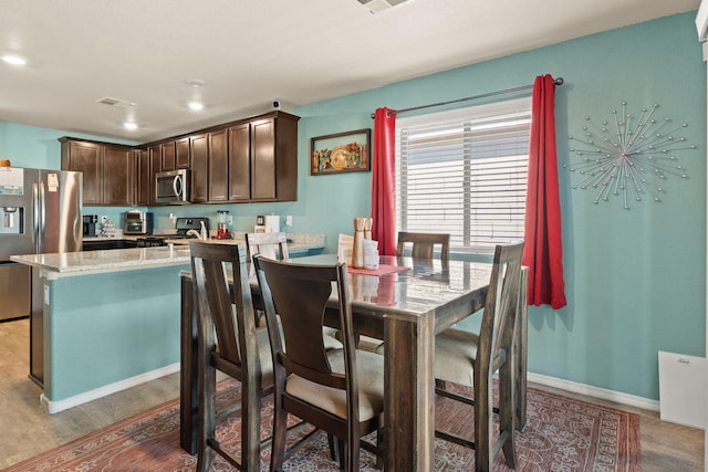 kitchen featuring dark brown cabinetry, stainless steel appliances, wood finished floors, visible vents, and baseboards