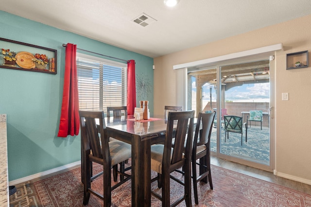 dining area featuring a wealth of natural light, wood finished floors, visible vents, and baseboards