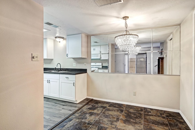 kitchen featuring dark countertops, white appliances, white cabinetry, and a sink