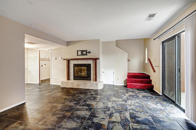 unfurnished living room featuring stairway, baseboards, a fireplace, and visible vents