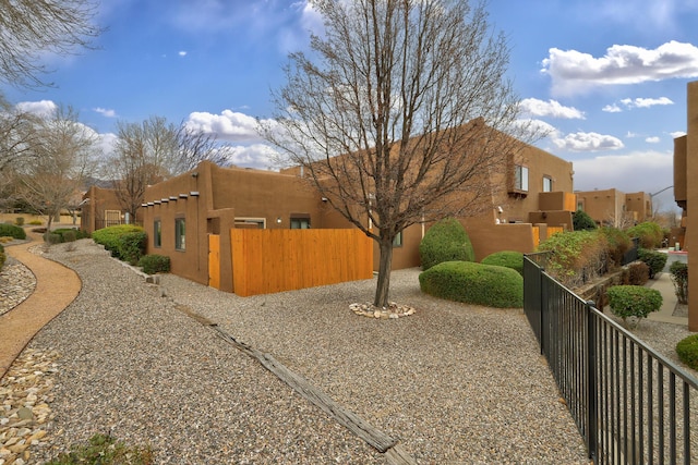 view of side of property with fence, a residential view, and stucco siding