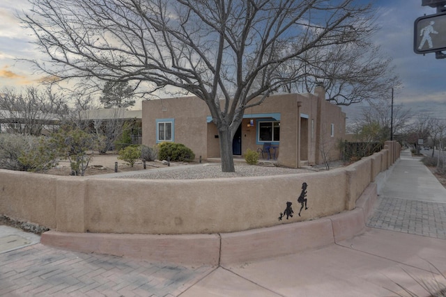 pueblo-style house featuring a fenced front yard and stucco siding