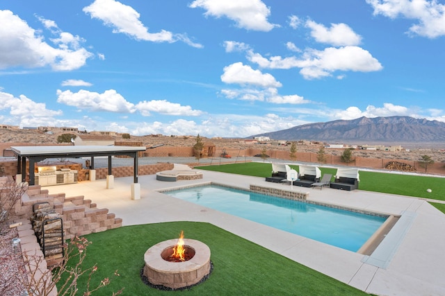 6316 La Paz Rd NE, Rio Rancho, NM 87144 - view of swimming pool with an outdoor kitchen, an outdoor fire pit, a patio, and a mountain view