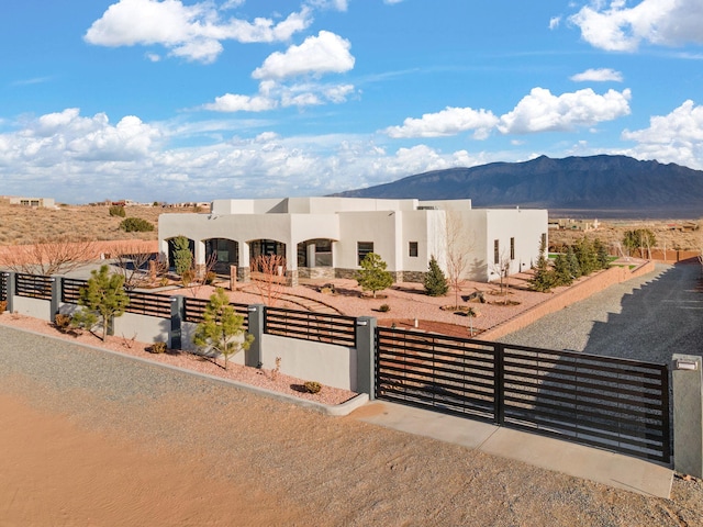 6316 La Paz Rd NE, Rio Rancho, NM 87144 - pueblo-style house with a fenced front yard, a mountain view, stucco siding, and a gate