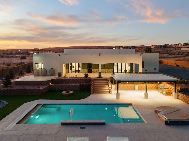 6316 La Paz Rd NE, Rio Rancho, NM 87144 - back of house at dusk with a fire pit, a patio, an outdoor pool, and stucco siding