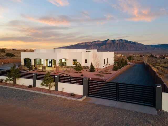 adobe home with a fenced front yard, a mountain view, and stucco siding