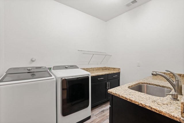 6316 La Paz Rd NE, Rio Rancho, NM 87144 - laundry area featuring washing machine and dryer, cabinet space, and light wood-style flooring