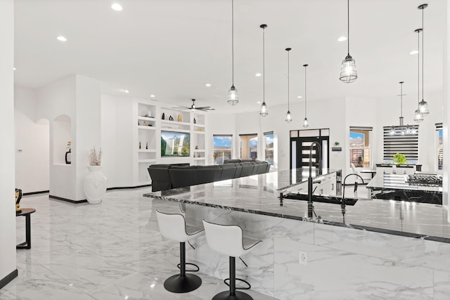 6316 La Paz Rd NE, Rio Rancho, NM 87144 - kitchen with built in shelves, light marble finish floors, dark stone countertops, recessed lighting, and ceiling fan