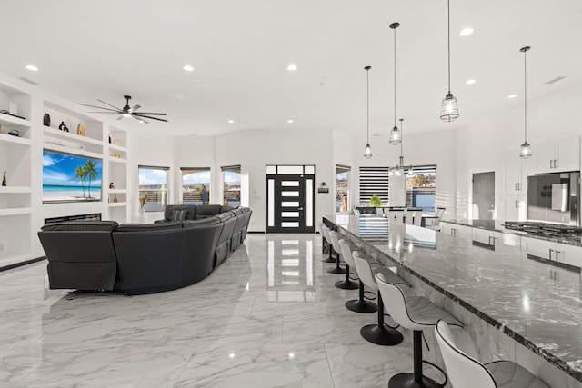 6316 La Paz Rd NE, Rio Rancho, NM 87144 - living area with built in shelves, a ceiling fan, recessed lighting, and light marble finish flooring