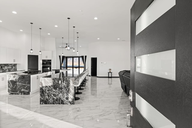 6316 La Paz Rd NE, Rio Rancho, NM 87144 - kitchen featuring a large island, a high ceiling, stainless steel double oven, recessed lighting, and light marble finish floors