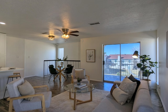 living room featuring baseboards, visible vents, ceiling fan, wood finished floors, and a textured ceiling