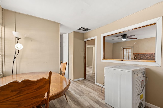 dining room featuring baseboards, light wood finished floors, washer / dryer, and a ceiling fan