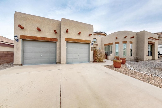 pueblo-style house featuring stucco siding and driveway