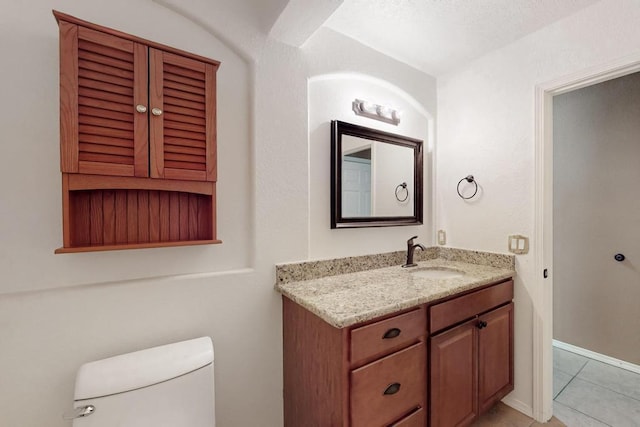 half bathroom with baseboards, vanity, toilet, and tile patterned floors