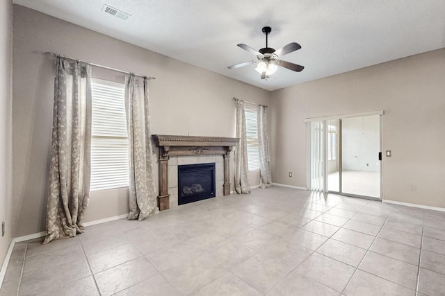 unfurnished living room featuring a tile fireplace, visible vents, ceiling fan, and baseboards