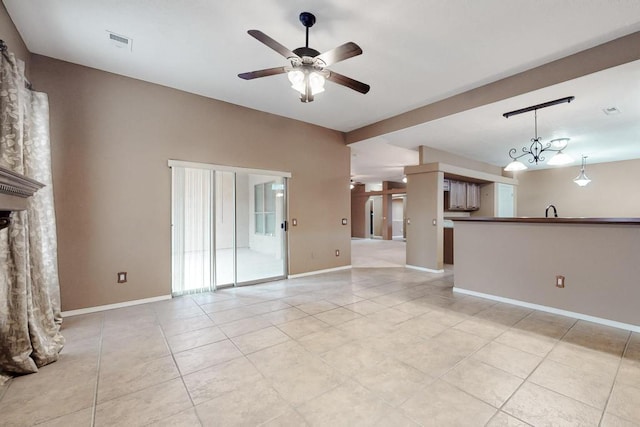 unfurnished living room with ceiling fan with notable chandelier, light tile patterned floors, visible vents, and baseboards