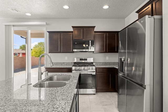 392 Pecos Loop SE, Rio Rancho, NM 87124 - kitchen with stainless steel appliances, a sink, dark brown cabinets, a textured ceiling, and light stone countertops