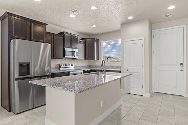 392 Pecos Loop SE, Rio Rancho, NM 87124 - kitchen with stainless steel appliances, a sink, light stone counters, dark brown cabinets, and a textured ceiling