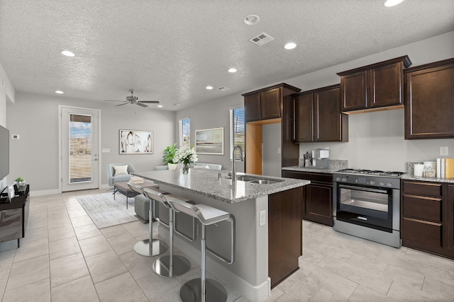 392 Pecos Loop SE, Rio Rancho, NM 87124 - kitchen with a sink, gas range, a ceiling fan, light stone counters, and a textured ceiling
