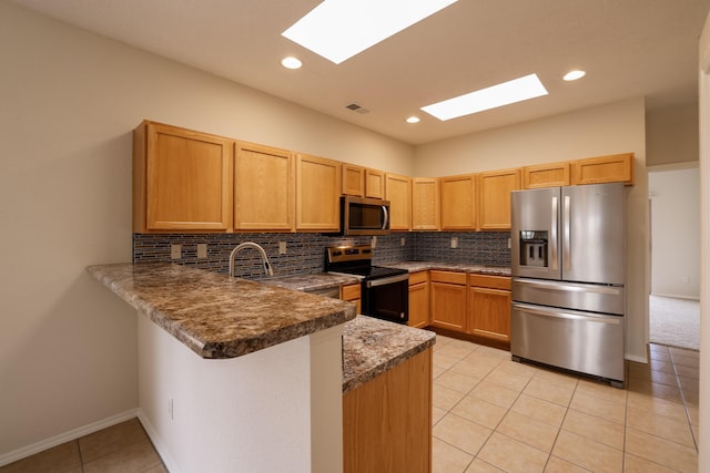 kitchen with a peninsula, visible vents, appliances with stainless steel finishes, and decorative backsplash