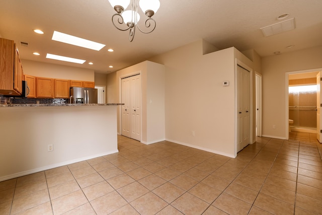 kitchen with light tile patterned floors, brown cabinetry, appliances with stainless steel finishes, decorative light fixtures, and recessed lighting