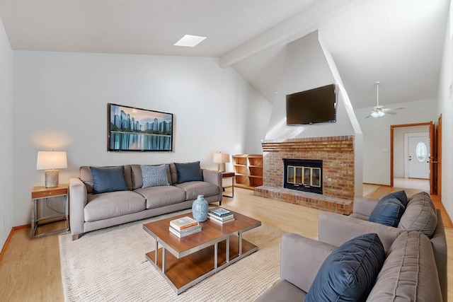 living area featuring lofted ceiling with beams, ceiling fan, a fireplace, and light wood-style floors