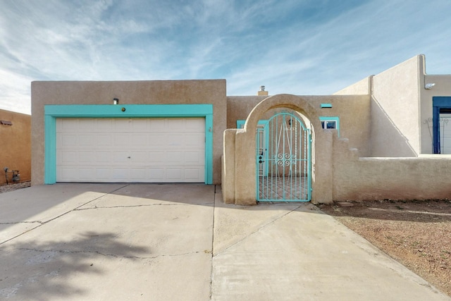 view of front of home featuring driveway, a garage, a fenced front yard, a gate, and stucco siding