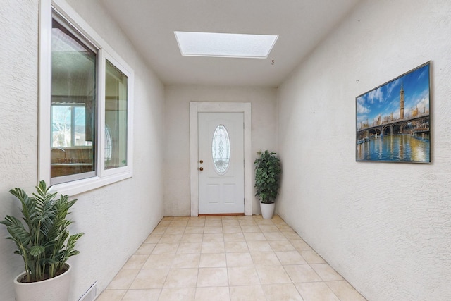 entryway featuring a textured wall, a skylight, and light tile patterned flooring