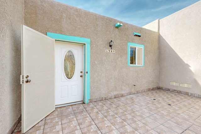 view of exterior entry with a patio area and stucco siding