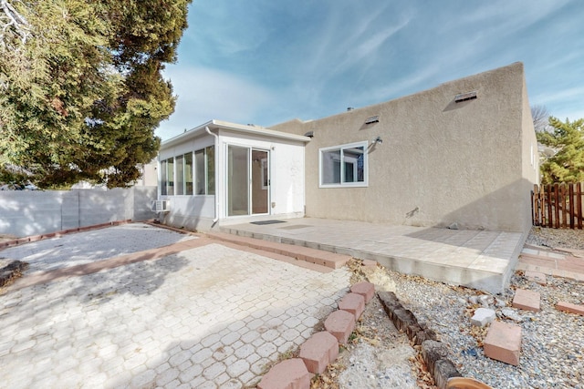 back of property with a patio, fence, a sunroom, and stucco siding