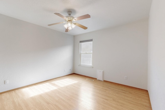 spare room featuring light wood-style floors, visible vents, baseboards, and a ceiling fan