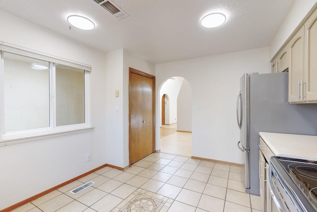 kitchen featuring light tile patterned floors, visible vents, arched walkways, and light countertops