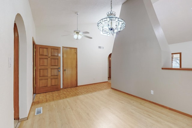 interior space featuring visible vents, arched walkways, ceiling fan, light wood-type flooring, and high vaulted ceiling